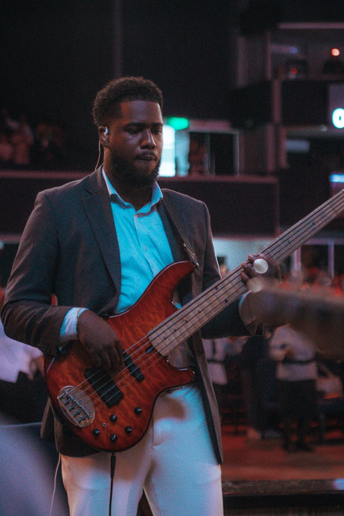 Male bassist performing indoors with vivid lighting and ambient atmosphere.